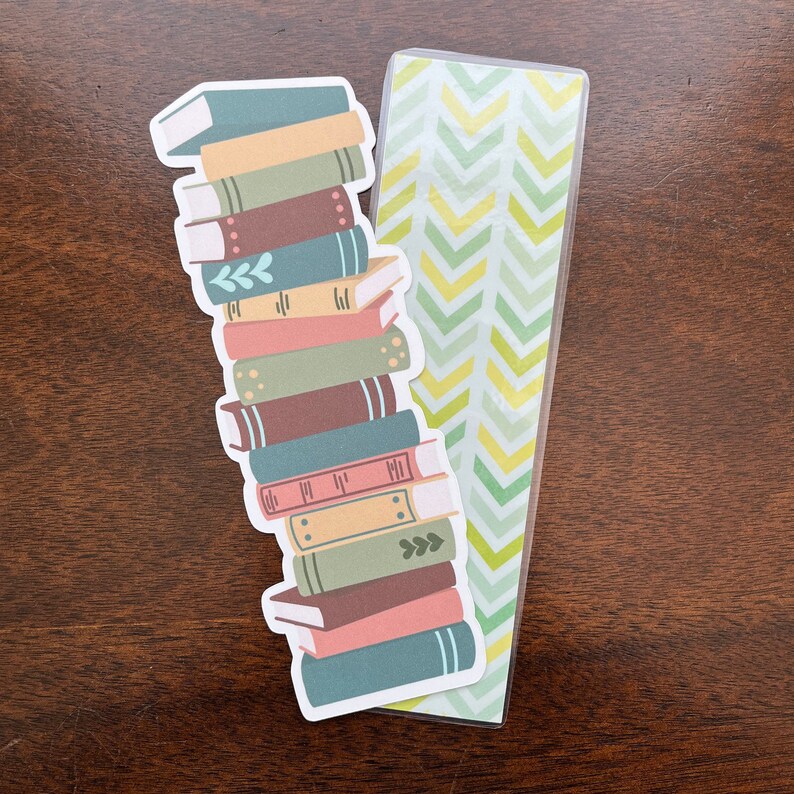 Peut inclure: Une pile de livres color&eacute;s avec un marque-page &agrave; motif chevron vert et jaune. Le marque-page est en plastique transparent avec un motif chevron vert et jaune.
