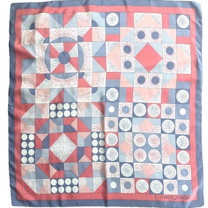 May include: Square scarf with a geometric pattern in shades of pink, blue, and white. The scarf features a border and the text "CHARLES JOURDAN" in the bottom right corner. The design includes squares, circles, and triangles.