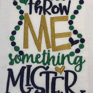 May include: White fabric with embroidered text and bead design. The text reads "throw ME something MISTER" in navy, gold, and green thread. The design includes heart and bead accents.