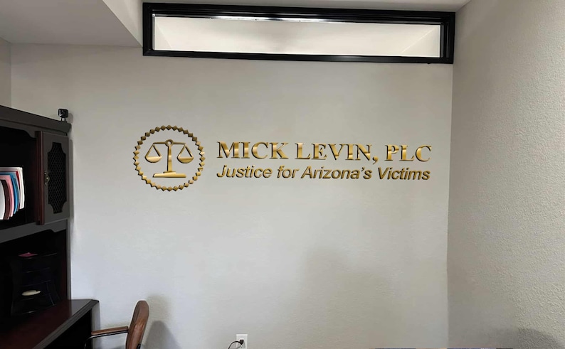 3D logo wall sign made with polished or brushed metal for a custom lobby sign in stainless metal on a dark wall in a modern conference room