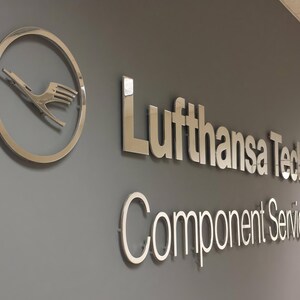 3D logo wall sign made with polished or brushed metal for a custom lobby sign in stainless metal on a dark wall in a modern conference room