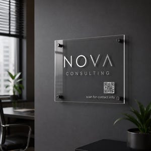 Könnte beinhalten: Transparente Acrylglas-Beschilderung mit silbernem Schriftzug "NOVA CONSULTING". Ein QR-Code und der Text "scan for contact info" befinden sich darunter. Das Schild ist an einer dunkelgrauen Wand befestigt.