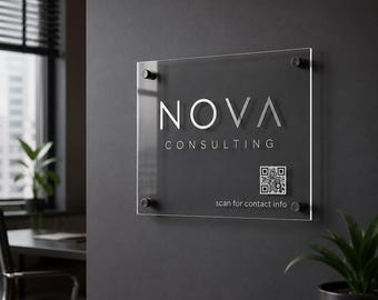 Pode incluir: Placa de acrílico transparente com o texto "NOVA CONSULTING" em letras prateadas. Um código QR e o texto "scan for contact info" estão abaixo. A placa está montada numa parede cinza escura.