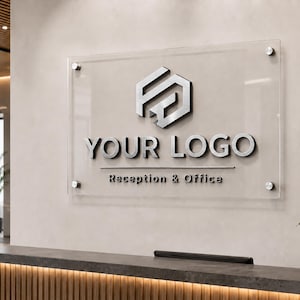 Könnte beinhalten: Ein klares Acrylschild mit silbernen Buchstaben und einem Logo ist an einer hellbeigen Wand angebracht. Auf dem Schild steht "YOUR LOGO" über "Reception & Office". Im Vordergrund befindet sich ein Empfangstresen mit Holzfront und dunkler Arbeitsplatte.
