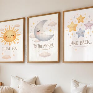 May include: Three framed art prints with a celestial theme. The prints feature a smiling sun with the text "I LOVE YOU", a crescent moon with "TO THE MOON", and stars with "AND BACK". The artwork has a soft, watercolor style.