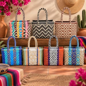 May include: Eight rectangular woven tote bags with two handles each, displayed in two rows. The bags feature various geometric patterns and color combinations, including bright multi-colored, black and white chevron, brown and white, and blue tones.