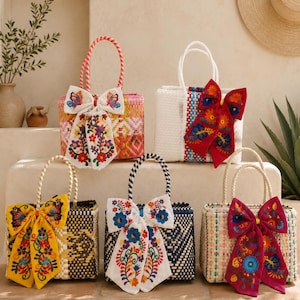 May include: Five rectangular woven tote bags with two handles each, decorated with large, colorful embroidered fabric bows. The bags feature various patterns and colors, including pink, white, yellow, navy blue, and beige, with floral embroidery.