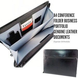 May include: Black leather A4 conference folder portfolio with zipper closure. The folder has multiple pockets and compartments for organising documents. The text "Tassia" is visible on the inside of the folder.