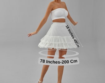May include: A white petticoat skirt with a layered design, 18 inches (45cm) in length, and a 78-inch (200cm) waist. The model is wearing a white tube top and white heels. The background is a solid gray.
