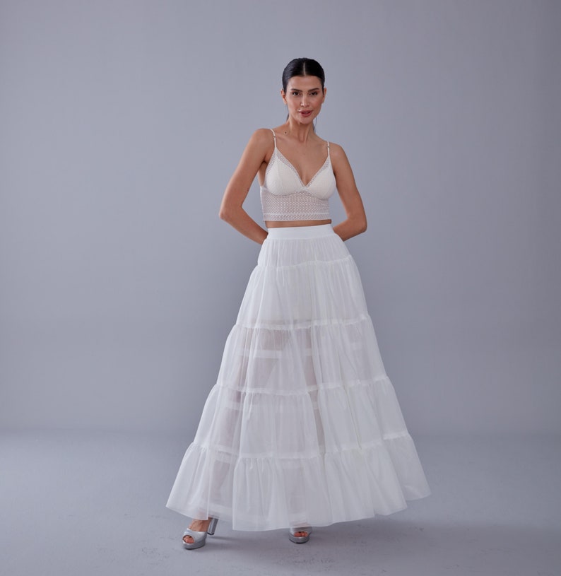 May include: A white, tiered maxi skirt with a lace crop top. The skirt has multiple layers of tulle and a fitted waistband.
