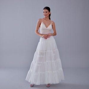 May include: A white layered maxi skirt with a ruffled hem. The skirt is made of a lightweight, flowy fabric and has a comfortable elastic waistband.