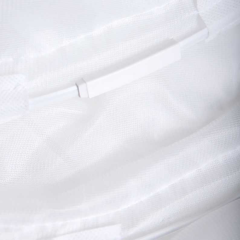 May include: White mesh fabric with a white plastic zipper pull. The zipper pull is attached to the fabric with a white cord.