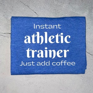 May include: Blue t-shirt with white text that reads "Instant athletic trainer. Just add coffee."