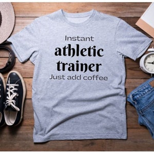May include: A gray t-shirt with the text "Instant athletic trainer Just add coffee" printed in black.