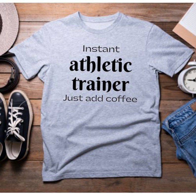 May include: A gray t-shirt with the text "Instant athletic trainer Just add coffee" printed in black.