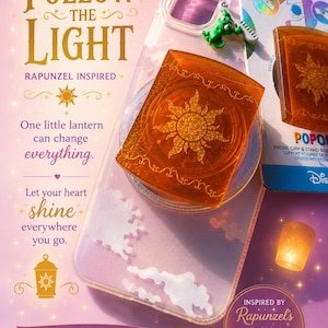 May include: A clear phone case featuring a small green chameleon figure and a square amber-colored phone grip with a gold sun emblem. The packaging includes text such as Introducing Follow The Light, Rapunzel Inspired, and PopSockets.