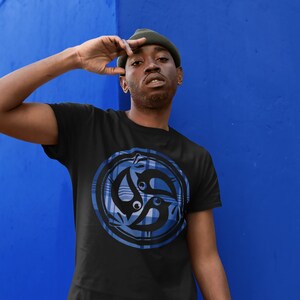 Może przedstawiać: Czarny t-shirt z niebiesko-białym wzorem w kratę, przedstawiający stylizowaną grafikę trzech ptaków w kółku.