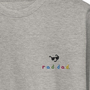 Puede incluir: Sudadera gris con un gráfico en blanco y negro de una cara con gafas de sol y el texto "raddad" en colores arcoíris.