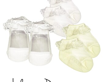 May include: A set of four baby socks, two white and two yellow, with lace trim. The socks are ankle-length and have a delicate, sheer fabric. The text "includes one pair" is visible at the bottom of the image.