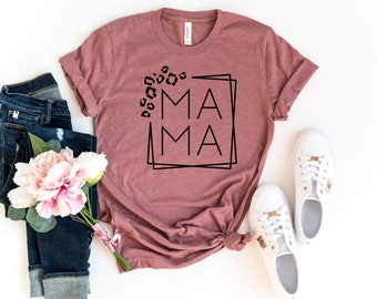 May include: A mauve t-shirt with a black graphic that says "MAMA" in a box with leopard print spots around it.