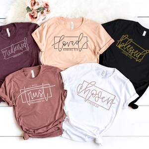 May include: Five different t-shirts with various bible verses printed on them. The shirts are in different colors, including maroon, peach, white, and black.