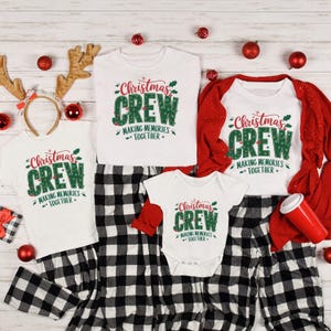 Puede incluir: Un conjunto de pijamas y camisetas navideñas a juego. Las camisetas blancas y el body presentan el texto "Christmas Crew" en verde y rojo. También se incluyen pantalones de pijama a cuadros blancos y negros, junto con decoraciones navideñas rojas y doradas.