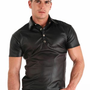 May include: A black leather short-sleeved shirt with a button-up collar and a silver button closure.