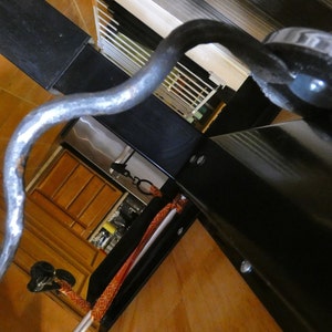 May include: A curved, silver-colored metal object with a textured surface, possibly a decorative hook or handle. The object is set against a backdrop of black surfaces and wooden cabinetry, creating a contrast in textures and colors.