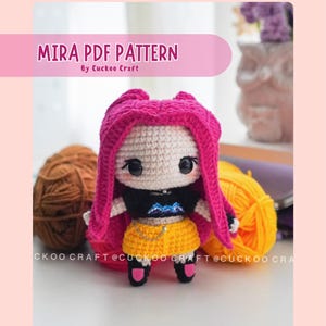 May include: A crocheted doll with a white face, black eyes, and vibrant pink hair. The doll is dressed in a black top, yellow shorts, and black shoes. The text "MIRA PDF PATTERN" is displayed above the doll.