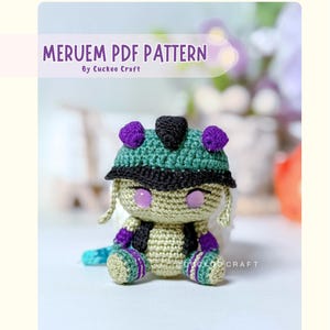 May include: A crochet amigurumi figure of a character with light green skin, purple eyes, and a green and black helmet. The figure has purple accents on the ears, arms, and legs. Text at the top reads MERUEM PDF PATTERN By Cuckoo Craft.