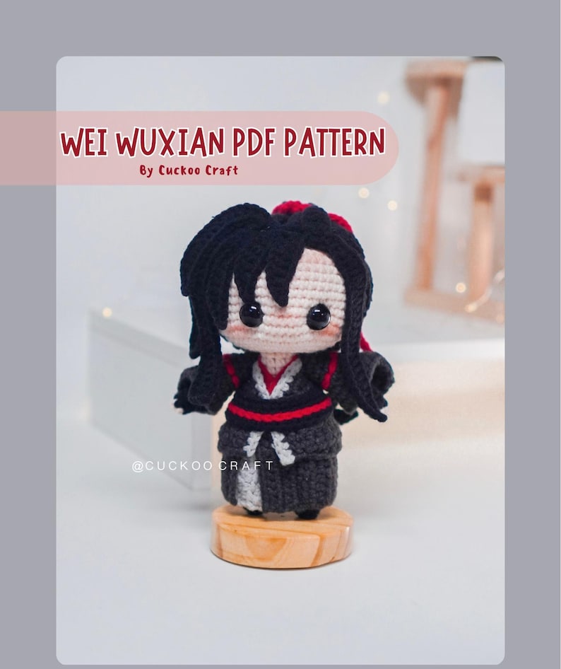 May include: A crocheted doll of a character with black hair and a red hair accessory, wearing a black and grey outfit with red accents. The doll is on a wooden base. Text on the image reads "WEI WUXIAN PDF PATTERN" and "By Cuckoo Craft".