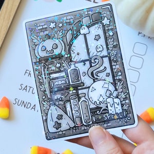 May include: A black and white illustration of a witch's apothecary with a pumpkin, potions, candles, a broom, and a skull. The illustration is on a holographic sticker with a glittery background.