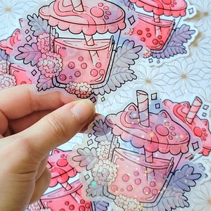 K&ouml;nnte beinhalten: Vier transparente Aufkleber mit einem rosa und wei&szlig;en Design eines Boba-Tees mit einem Katzenpfoten-Deckel und einem rosa und wei&szlig;en gestreiften Strohhalm. Der Boba-Tee ist von rosa Blumen und gr&uuml;nen Bl&auml;ttern umgeben.