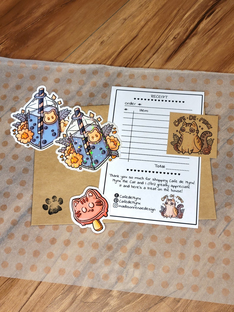 May include: A set of stickers featuring a cartoon cat with a boba tea drink. The stickers are on a brown paper background with a receipt from "Cafe de Mynx" and the text "Thank you so much for shopping Cafe de Mynx Mynx the Cat and I (Ari) greatly appreciate it and here's a treat on the house!"  The receipt also includes the text "Cafede Mynx" and "madisonrenaedesign".