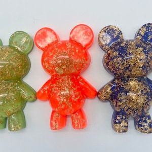 May include: Three resin teddy bear figurines with gold flecks. The bears are green, orange, and blue.