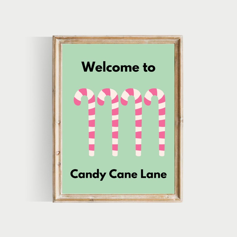 May include: A framed print with a green background and the text "Welcome to Candy Cane Lane" in black. Four pink and white candy canes are arranged vertically in the centre of the print.