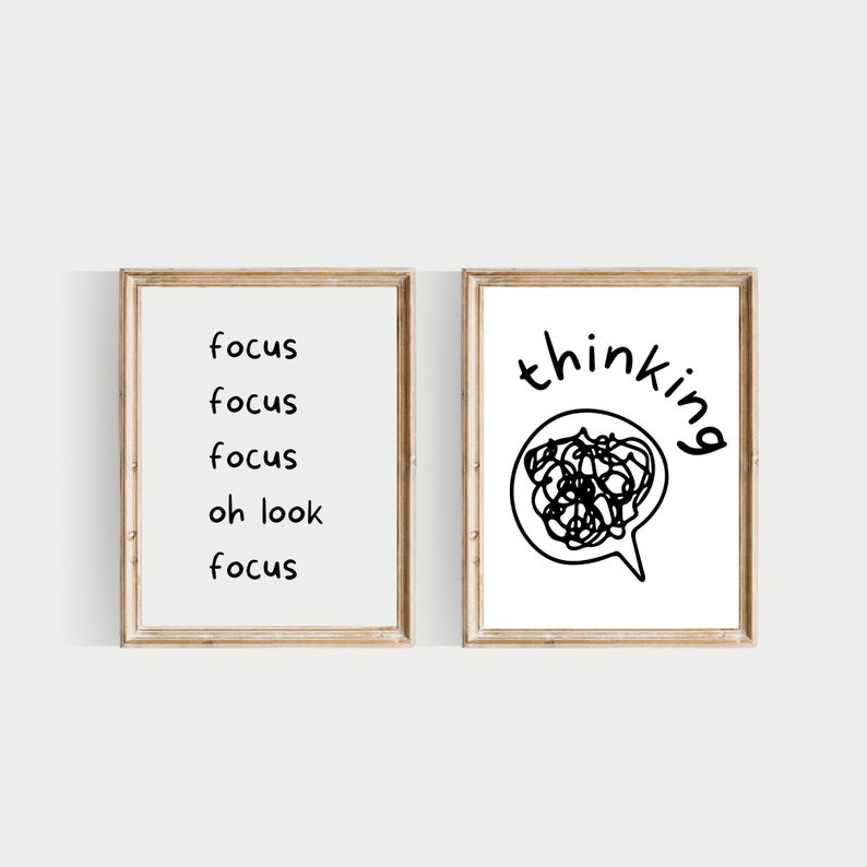 May include: Two framed prints with black text and illustrations. The left print says "focus" four times with the word "oh look" in between. The right print says "thinking" with a black and white illustration of a thought bubble with a messy scribble inside.