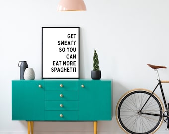 Puede incluir: Un aparador turquesa con pomos dorados y patas amarillas, con jarrones decorativos y una planta en maceta. Un cartel enmarcado dice "Get Sweaty So You Can Eat More Spaghetti". Una bicicleta se apoya en la pared y una lámpara colgante rosa cuelga encima.