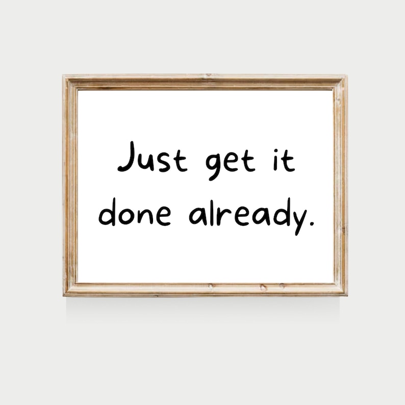 May include: A framed motivational quote that reads "Just get it done already." The frame is light brown wood with a white background.