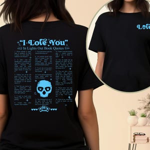 May include: Black t-shirt with the text "I Love You" and quotes from "Lights Out" in light blue. The back features a skull graphic and playing card symbols. The front has the word "Love" in light blue.