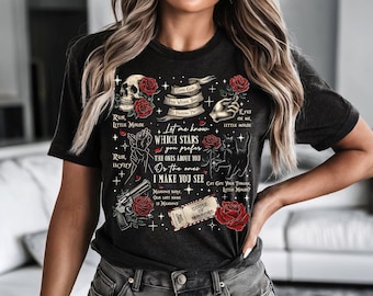 May include: Dark gray t-shirt with a skull, roses, and various graphics. Text includes "Good Girls", "Let me know which stars you prefer", and "House of Mirrors". The design features a hand, a cat, and a gun.