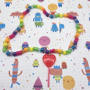 The pink lollipop necklace is splayed out fully, displaying the entire beaded length