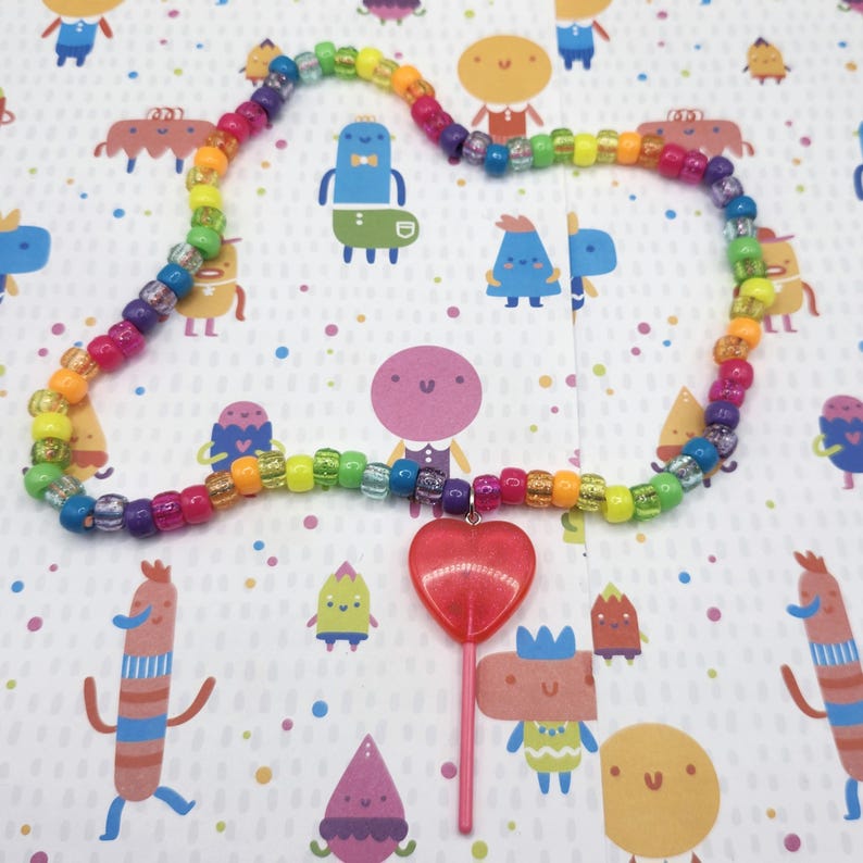 The pink lollipop necklace is splayed out fully, displaying the entire beaded length