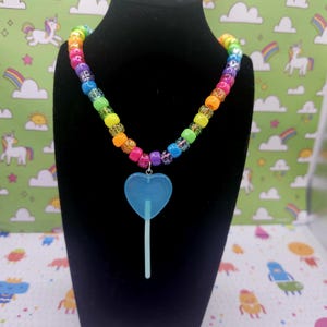 A neck model is wearing the blue lollipop necklace