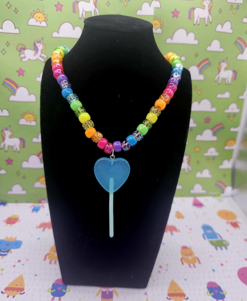 A neck model is wearing the blue lollipop necklace