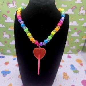 A neck model is wearing the pink lollipop necklace