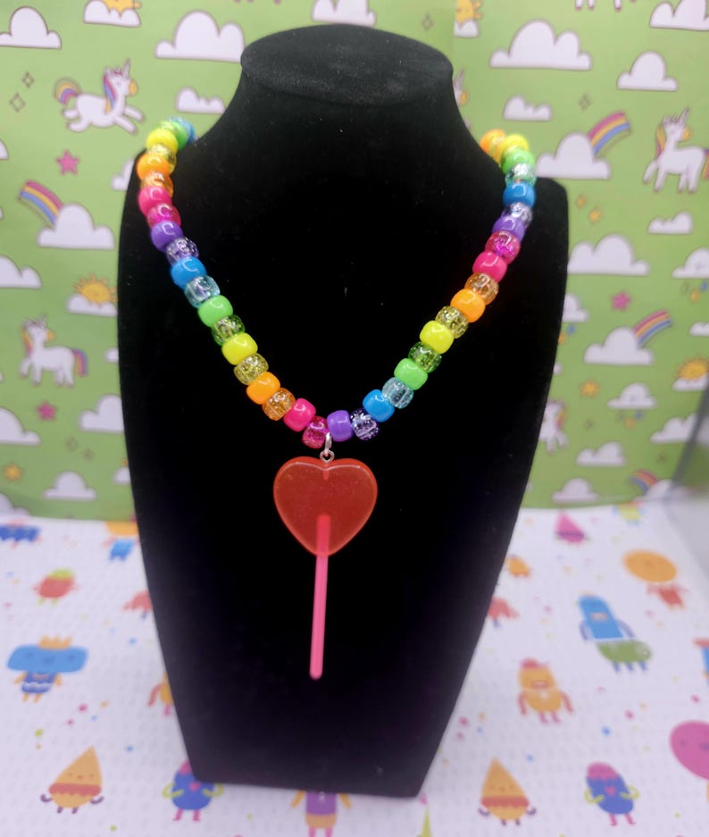 A neck model is wearing the pink lollipop necklace