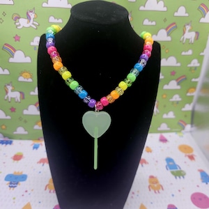 A neck model is wearing the green lollipop necklace
