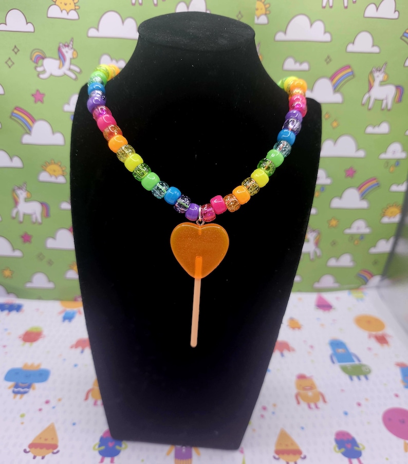 A neck model is wearing the orange lollipop necklace