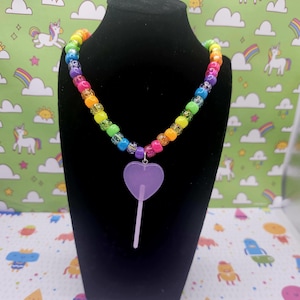 A neck model is wearing the purple lollipop necklace